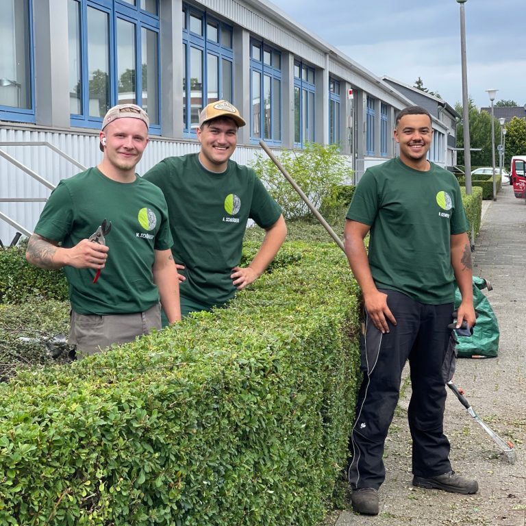 Team SchönherrGarten Drei Männer in grünen T-Shirts stehen neben einer geschnittenen Hecke.