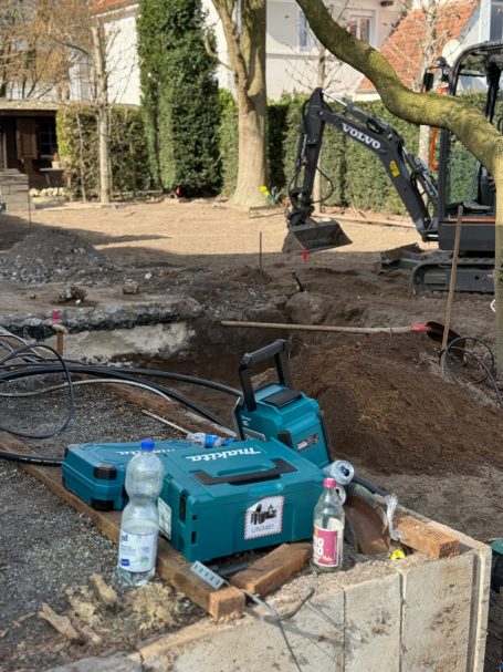 Werkzeuge und Maschinen auf einer Baustelle, darunter eine Wasserflasche und eine Sprühflasche.
